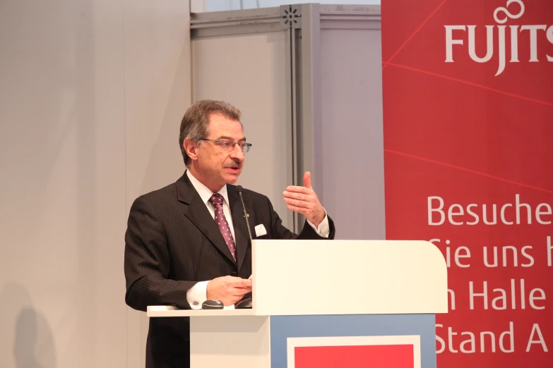 a man in glasses and a suit giving a speech