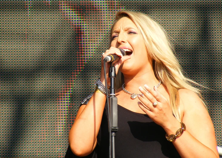 the blond woman is singing on stage in front of the crowd
