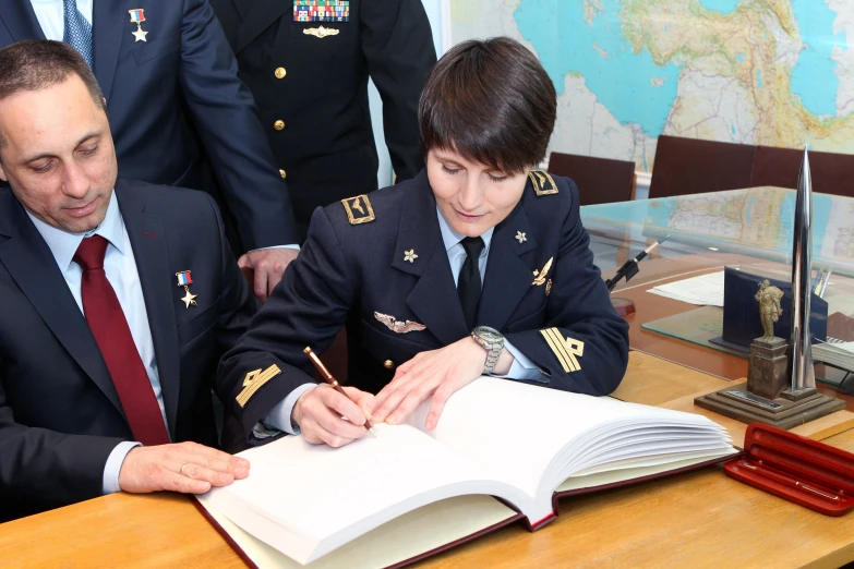 two air force men sitting at a desk signing documents