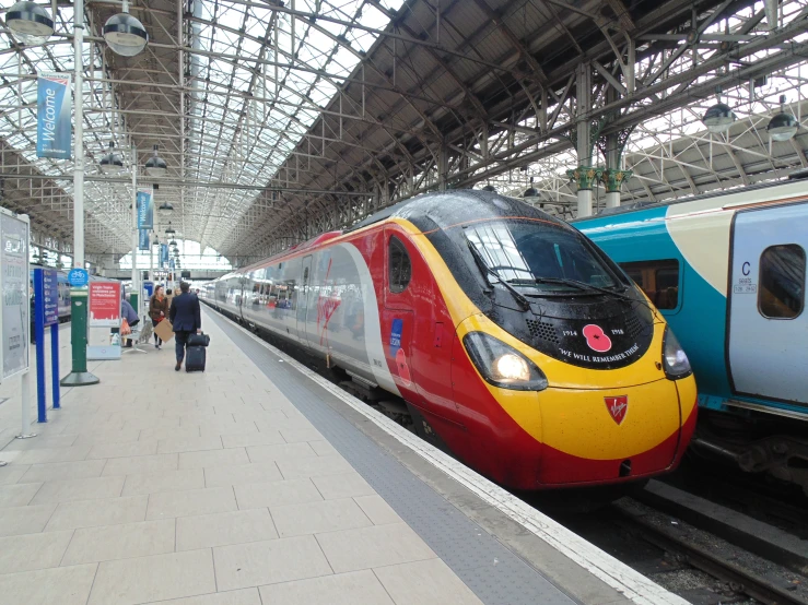 two trains stopped at a train station and passengers are near the platform