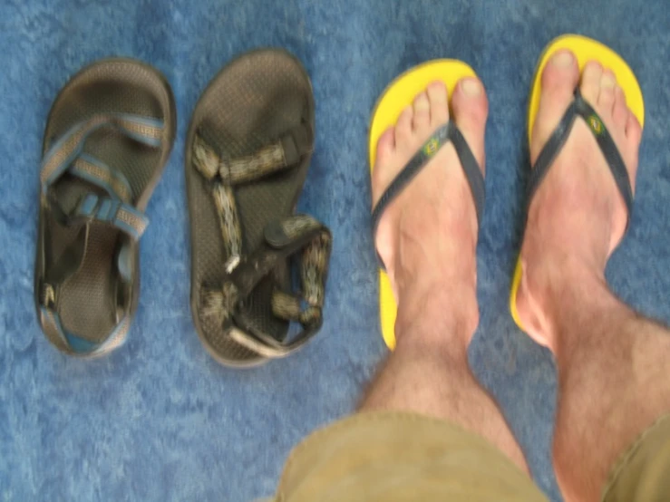 four pairs of sandals and a man's feet on the floor