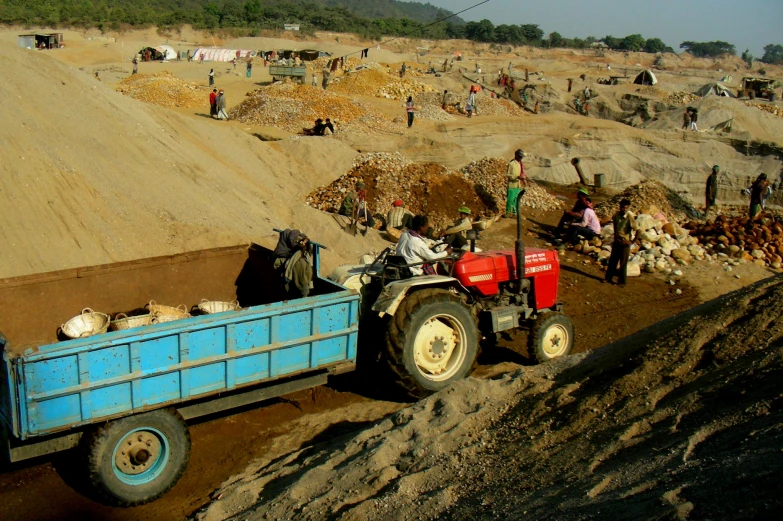 a small tractor hauling sand in a open area