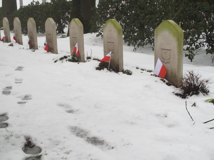 a group of headstones and flags sticking out of the snow