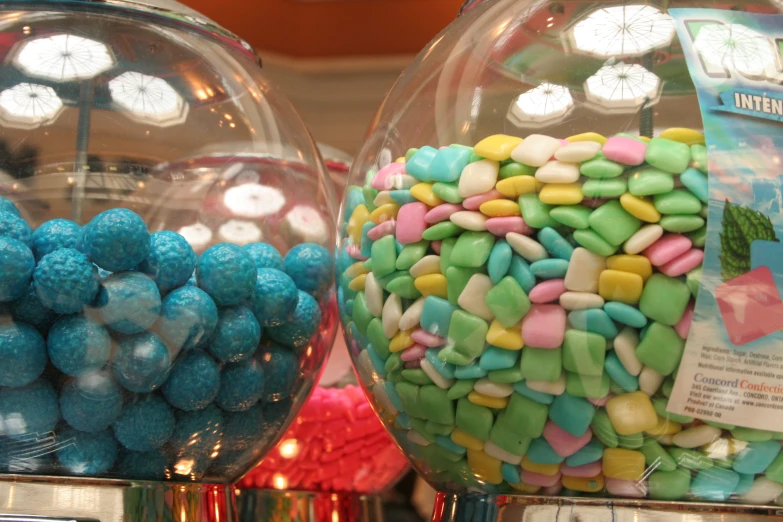 a couple of round clear glass vases holding different colored sweets