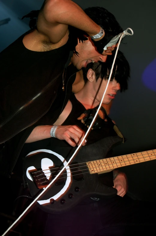 two male guitarists in black vests one is playing