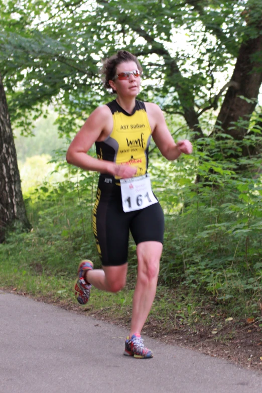 a male runner in yellow vest and black shorts