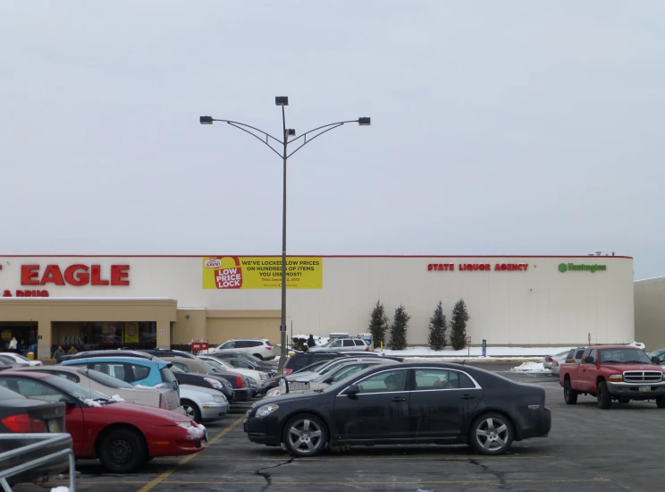 cars are parked in the lot next to a eagle store