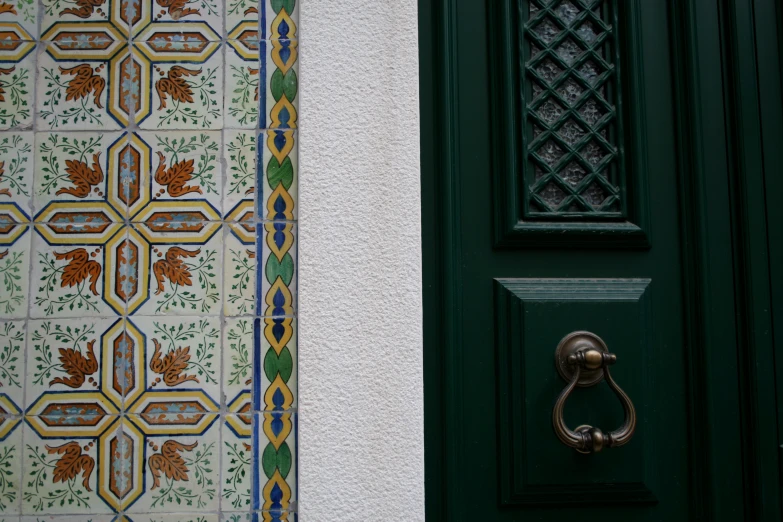 there is an ornamental green door handle in front of the doorway