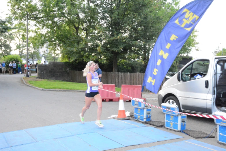 a woman running down the side walk near a blue flag