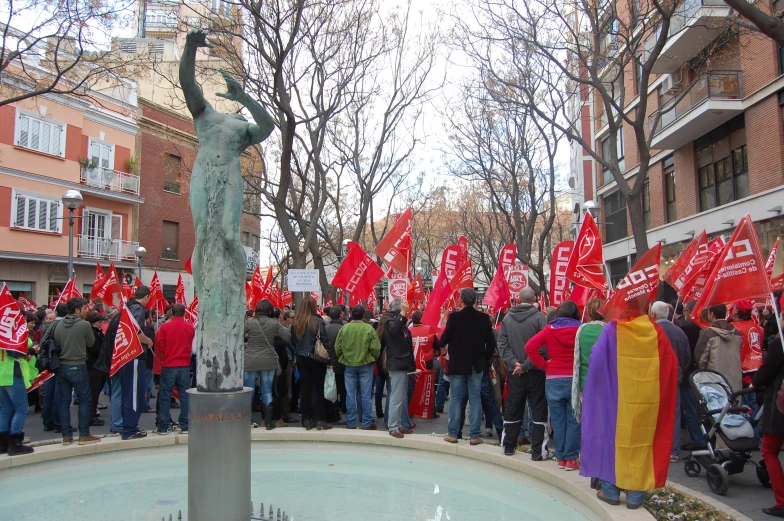 a group of people are gathered around a fountain with red signs and a statue