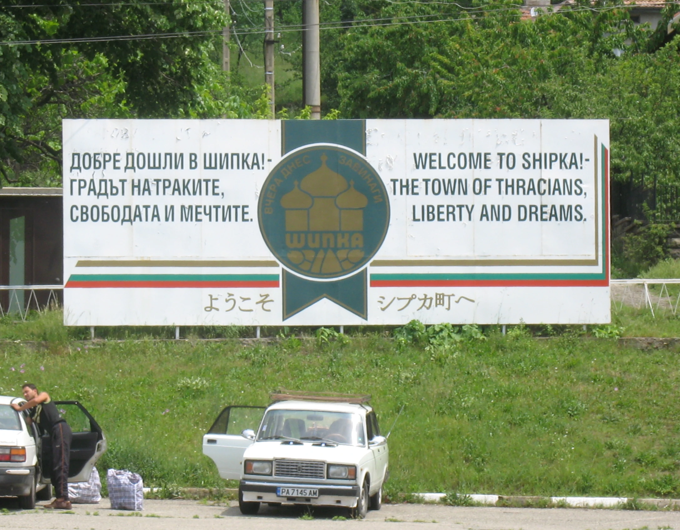 two cars parked outside near a welcome to sappor sign