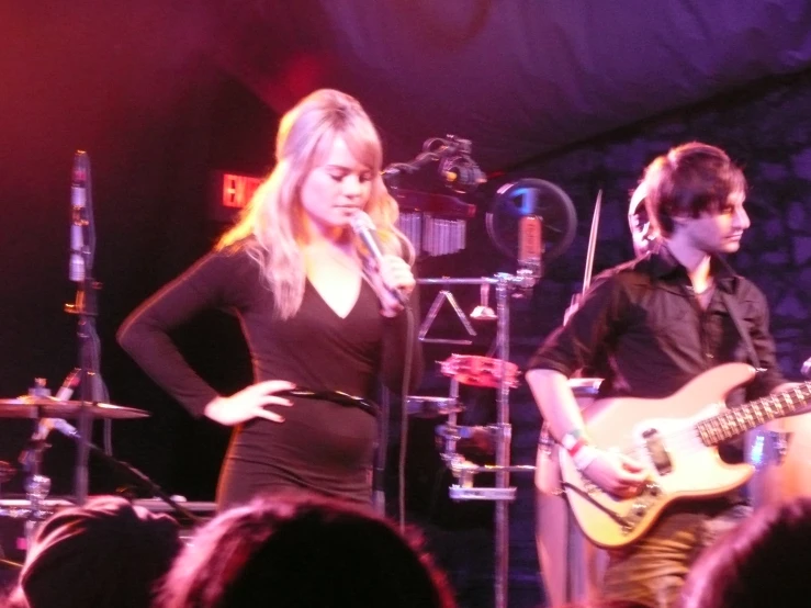 two people playing guitar and singing on stage