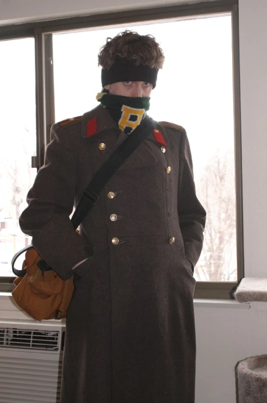 a man with a face bandana and coat is in a window