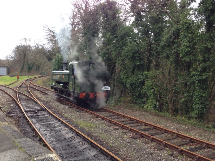 a steam engine riding down the tracks near trees