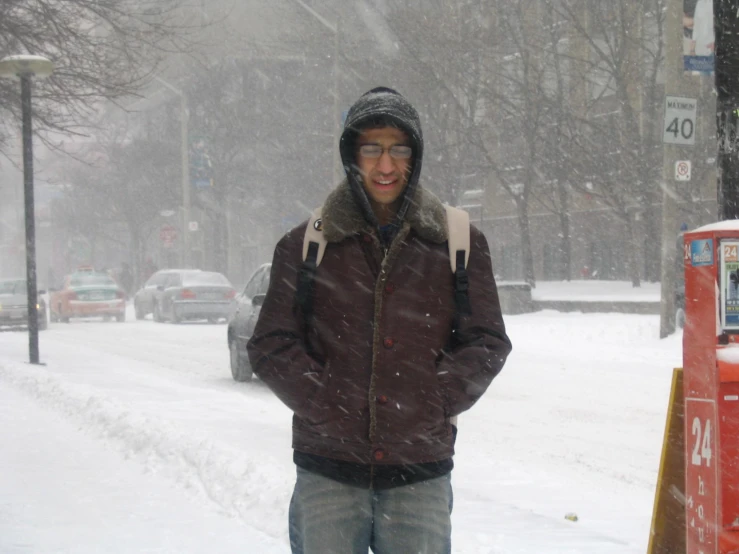 a man standing in a snowy city near parking meters