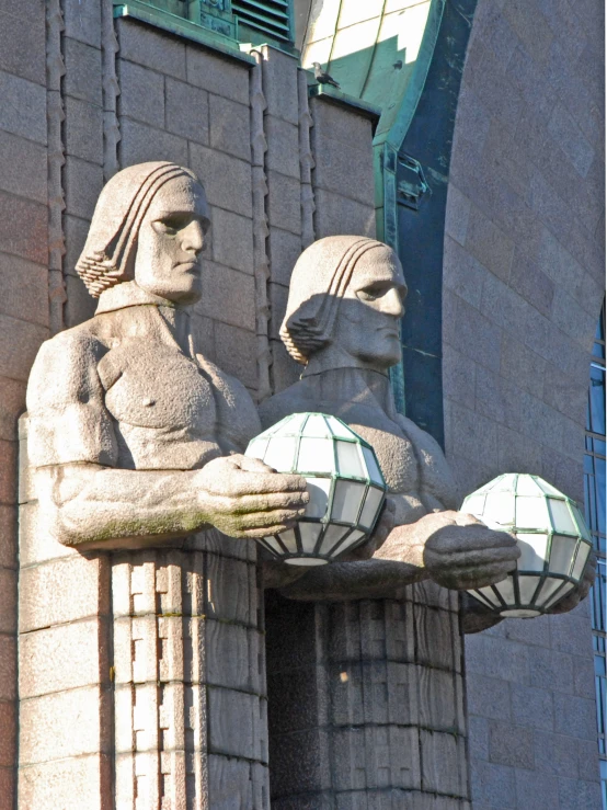 statues of women and men holding up balls