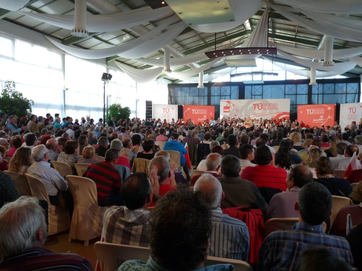 many people in chairs are listening to a speaker