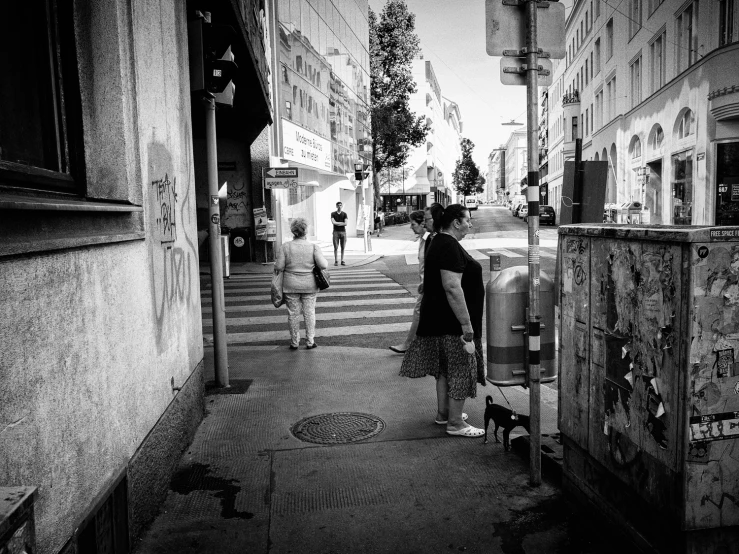 two women are on the sidewalk next to the road