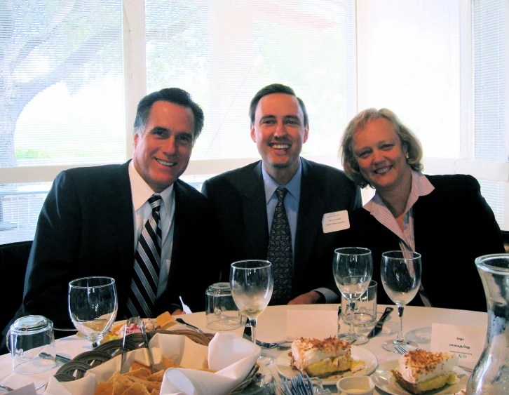 two men and a woman seated at a table with wine glasses