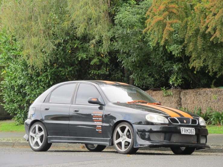 a grey car with an orange stripe parked on the side of the street