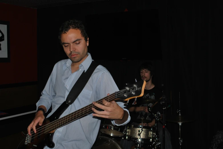 man playing bass on stage with band on one side of the wall