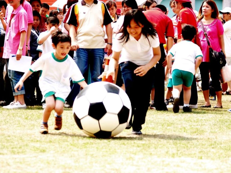 a boy and girl playing with a large soccer ball