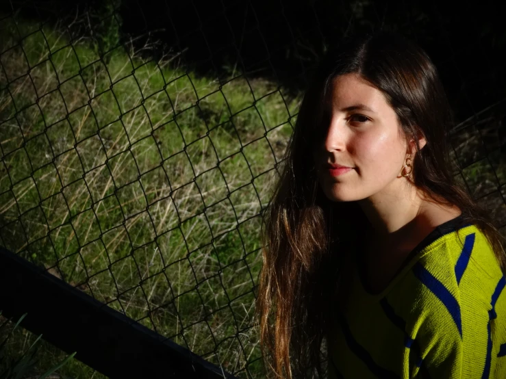 young woman next to fence in grassy area at dusk