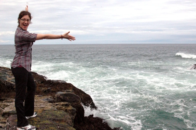 a person standing on a rocky cliff next to the ocean