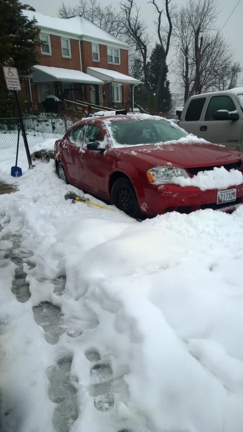 a car on snowy street with a house in background