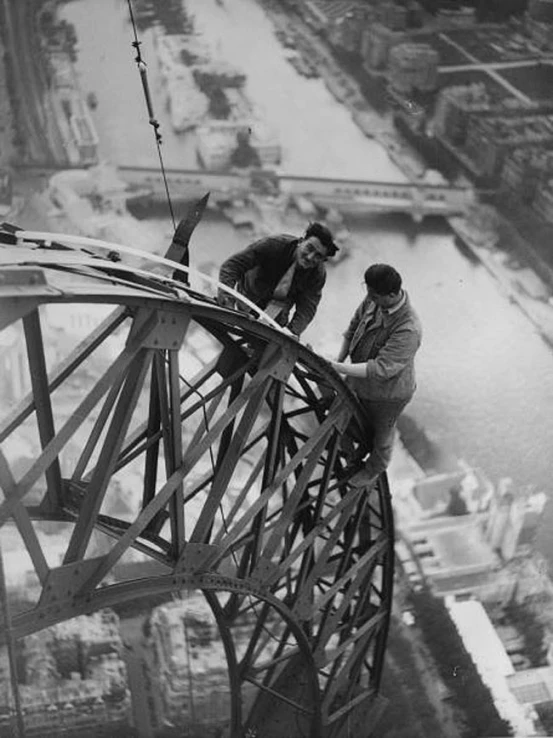 men climbing up and down a high bridge on snow covered roofs