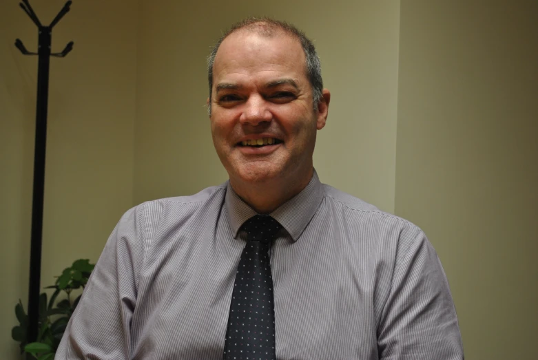 a smiling man wearing a long tie in a room