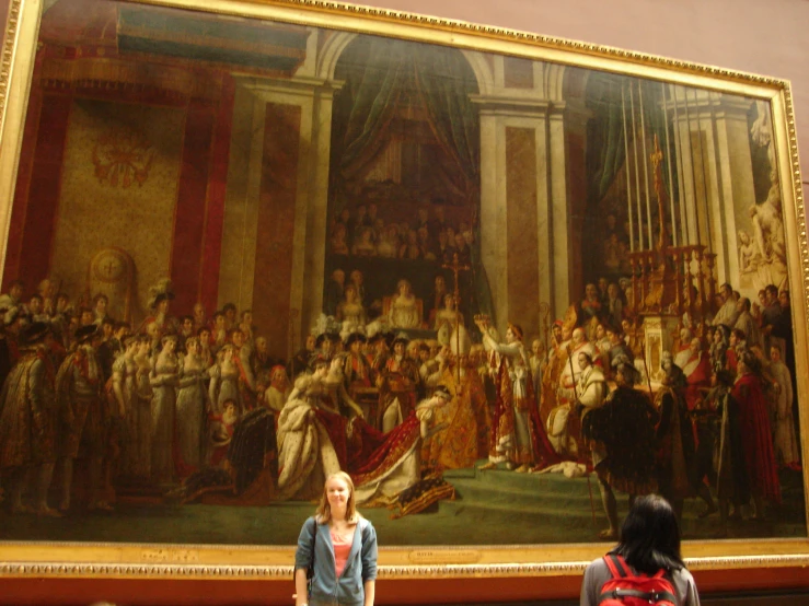 a woman in front of a painting of a large crowd