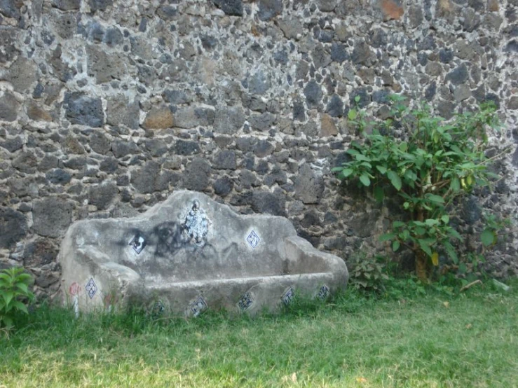 a cement bench sitting next to a stone wall
