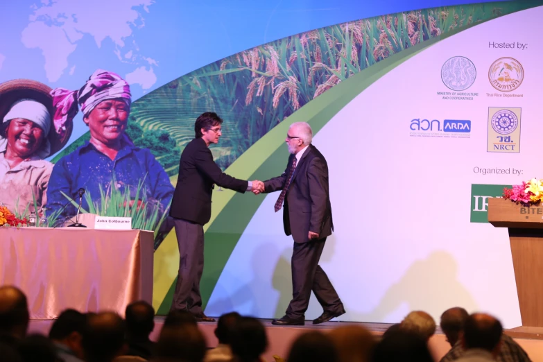 two men are shaking hands on a stage