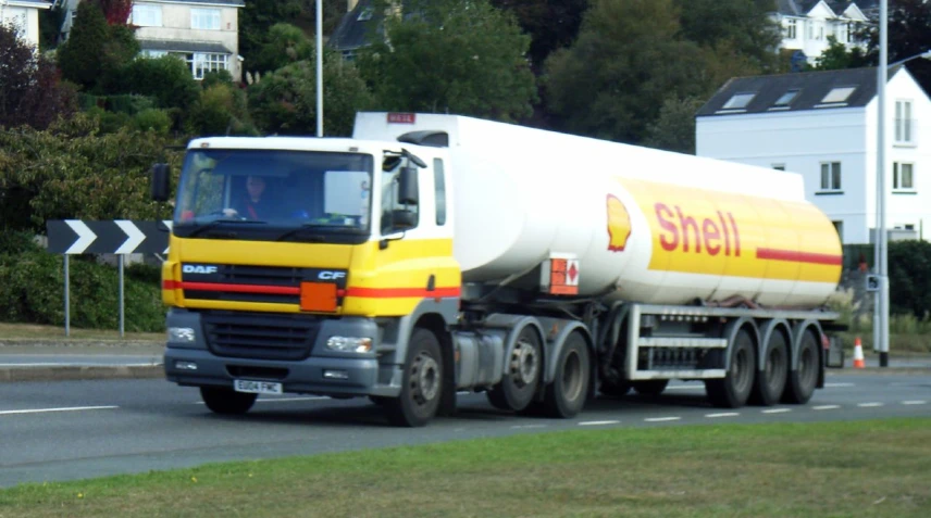 a tanker truck drives on the road by some houses