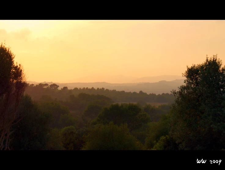 the sun setting on a valley in the hills