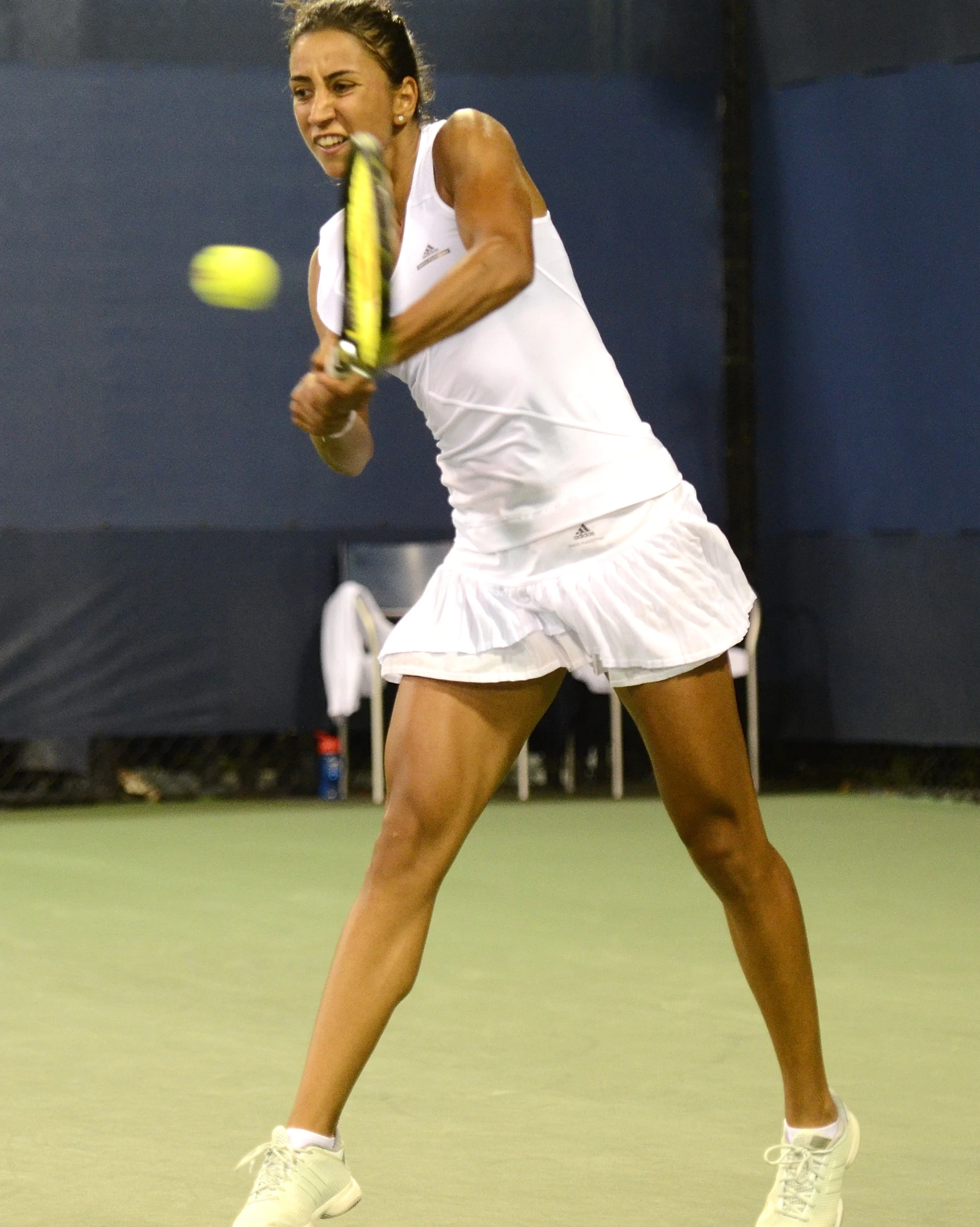 a young lady swinging a tennis racquet towards a tennis ball