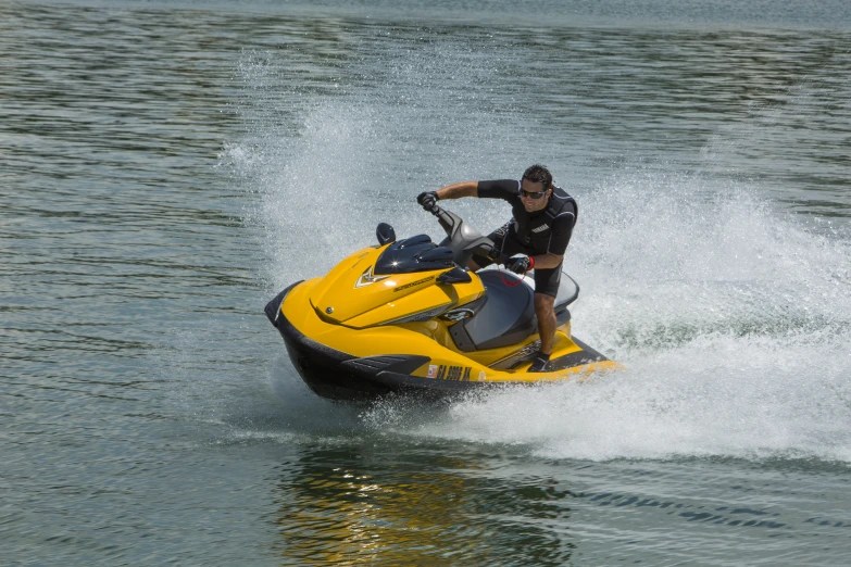 a man in black shirt riding a yellow and black jet ski