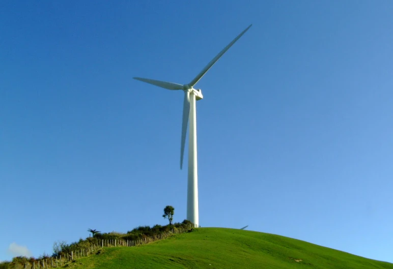 a white wind turbine towering above a lush green hillside