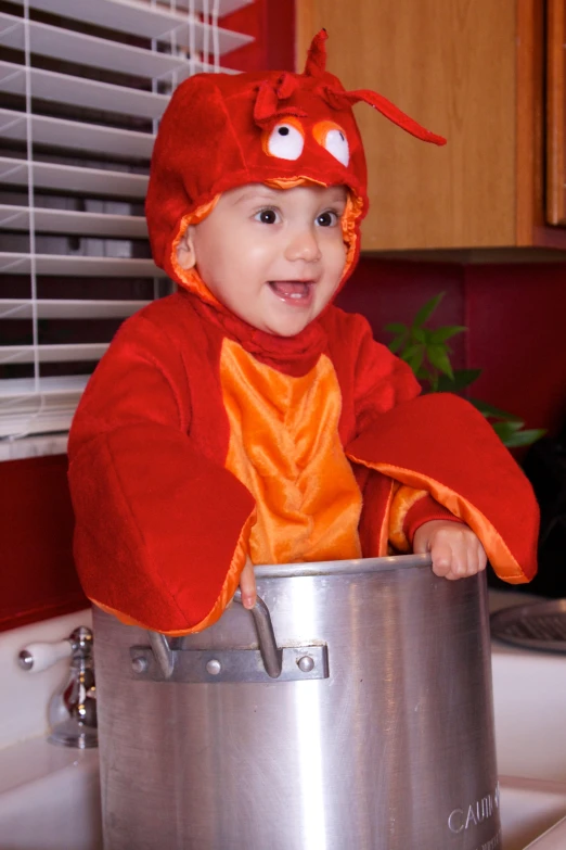 a little baby in a lobster costume holding onto a pot