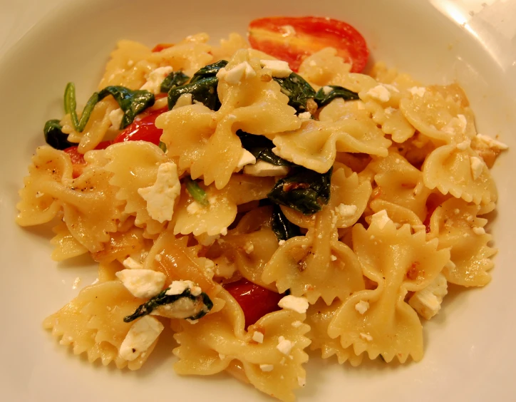 a bowl filled with noodles and cheese next to a tomato