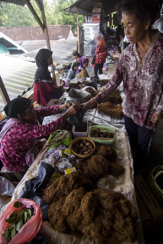 two woman at an outdoor market with various foods