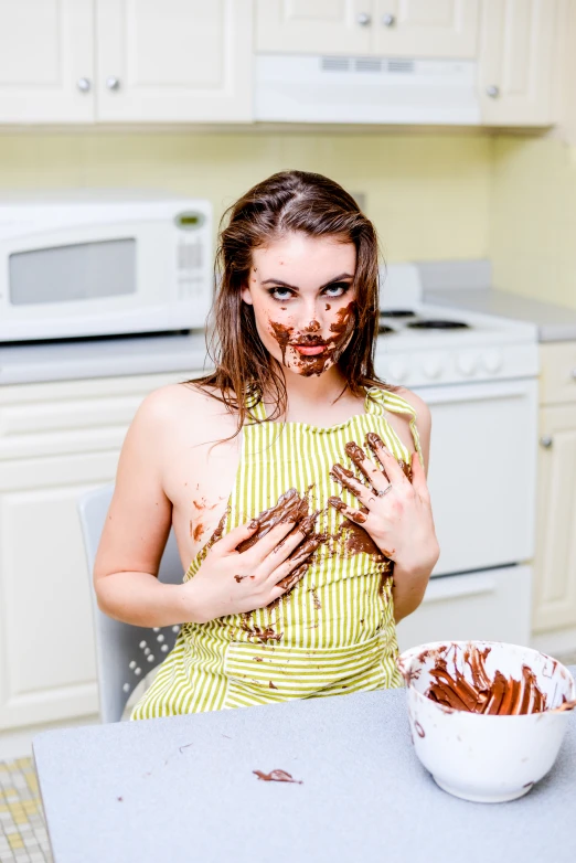 a person eating cake in the kitchen with a bowl of icing