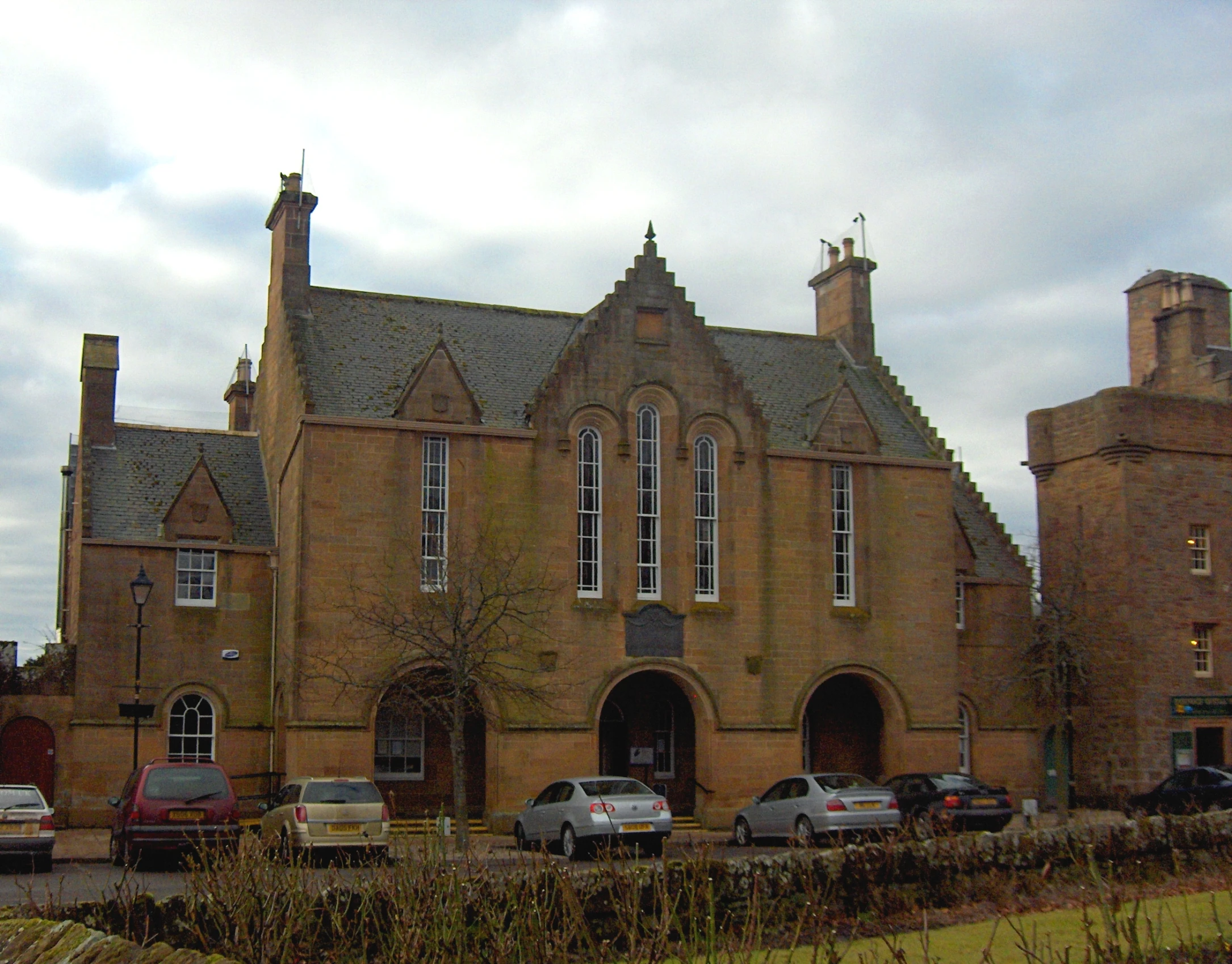 some cars parked in front of a large brown building