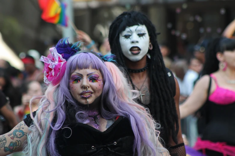 two women dressed up with face paint, wearing black and pink hair