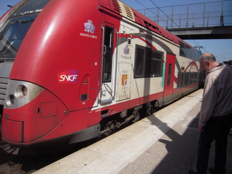 a passenger train parked next to a platform with its conductor