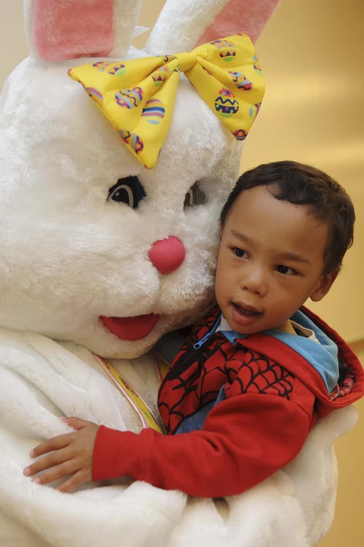 a little boy hugging his mother's bunny in front of a large stuffed animal