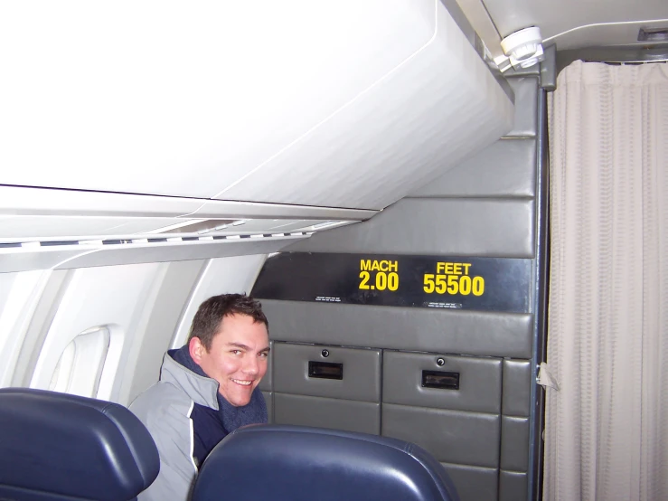 a smiling man sitting on an airplane looking out the window