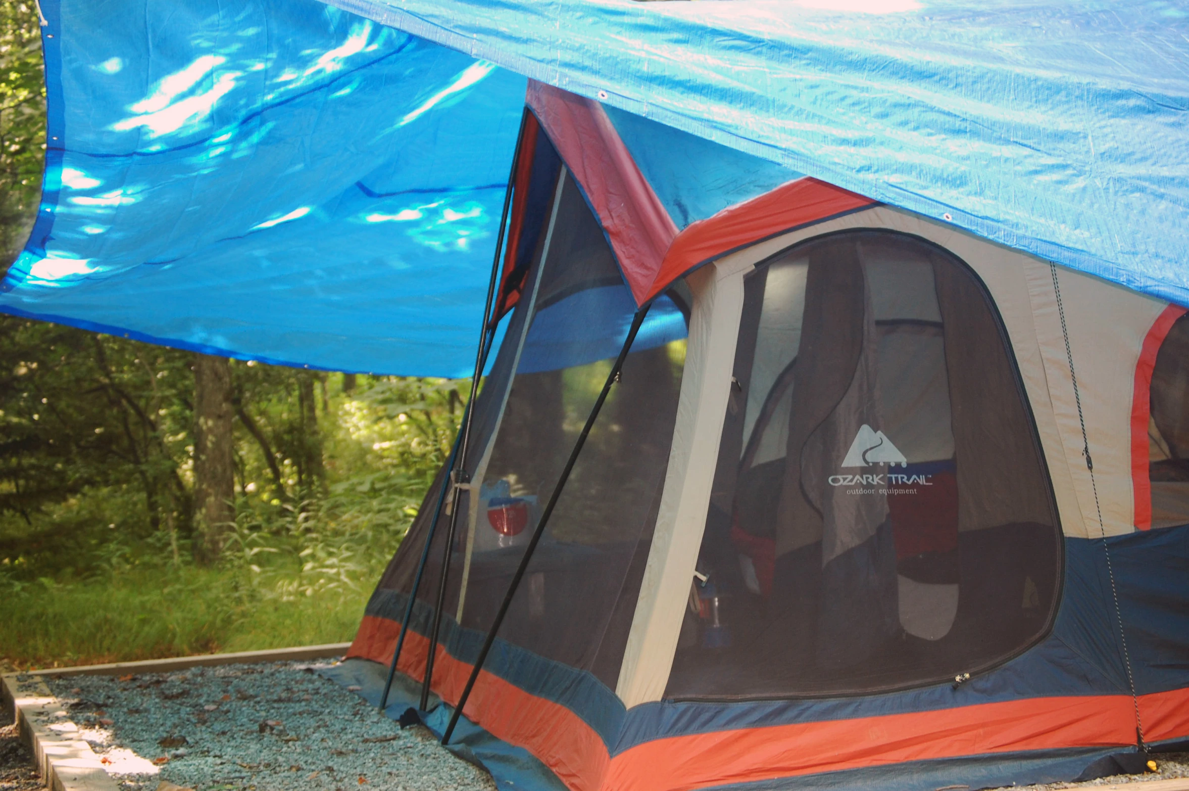 a tent in the woods has a blue canopy