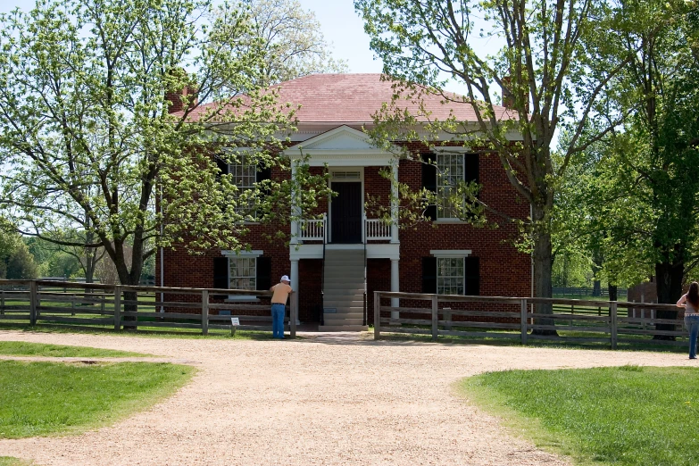 two people in front of an old brick house on dirt